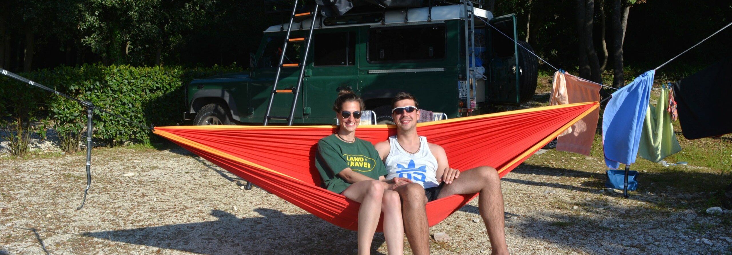 Full-time car travellers with camping gear setup in the background short